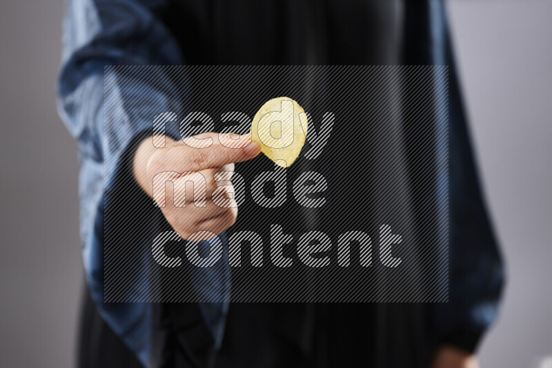 Woman in abaya holding different kinds of snacks in different positions