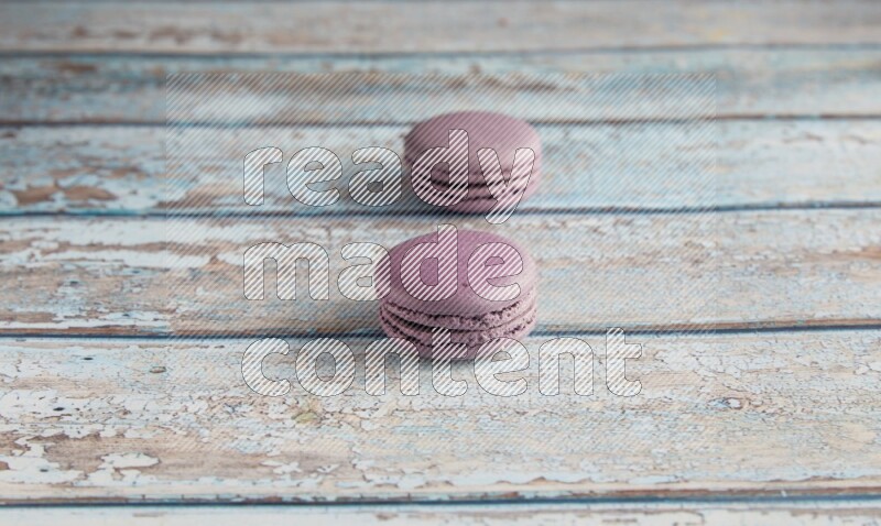 45º Shot of two Purple Blueberry macarons on light blue wooden background