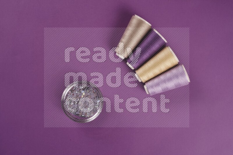 A beige collection of sewing and tailoring tools arranged on a purple background