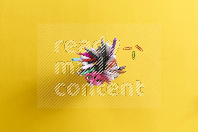 Pens, pencils and school supplies in a pen holder on yellow background (Back to school)