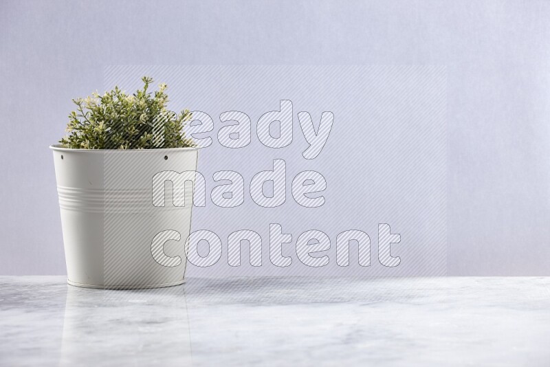 Artificial plant in white pot on grey marble background