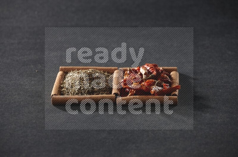 مربعان من أعواد القرفة ممتلئان بالفلفل الحار المجفف وحبوب الكمون علي خلفية سوداء