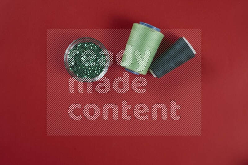 A green and red collection of sewing and tailoring tools arranged on a red background