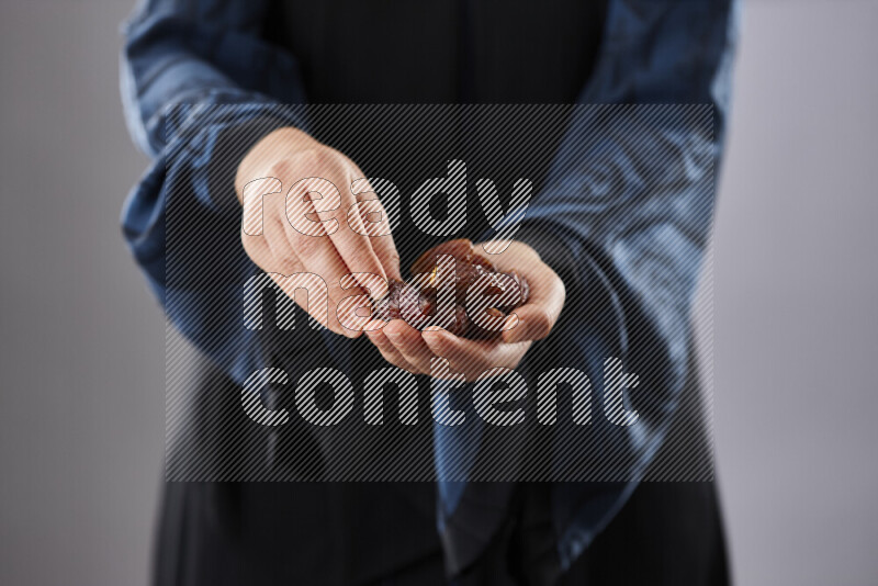 Woman in abaya holding dates in different positions