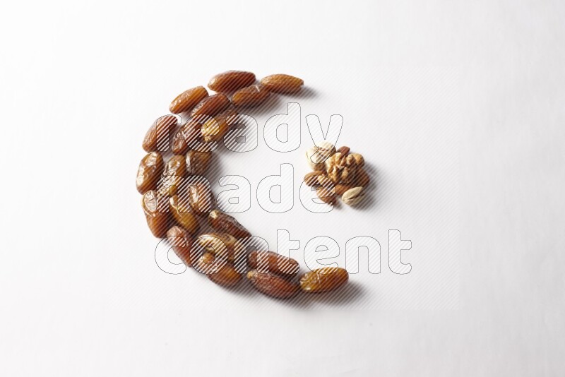 Dates in a crescent shape with nuts on white background