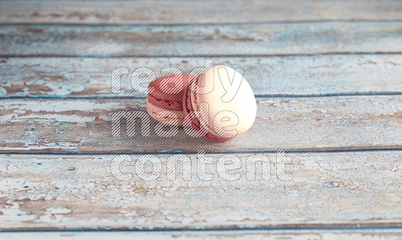 45º Shot of two Pink Litchi Raspberry macarons on light blue wooden background