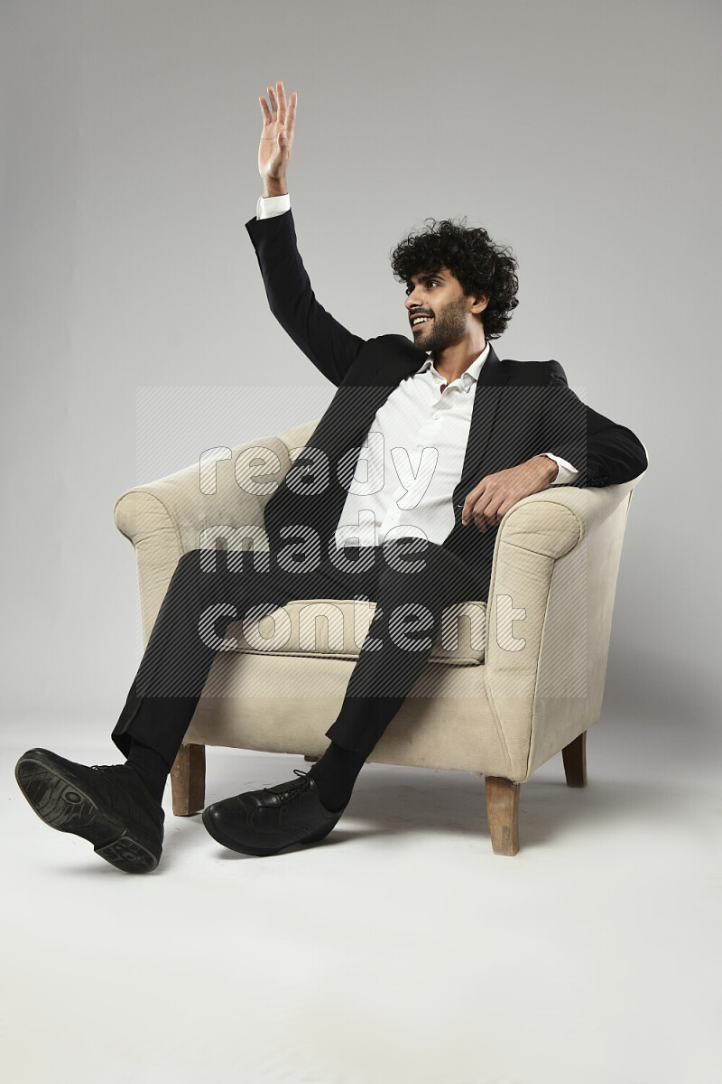 A man wearing formal sitting on a chair making a hand gesture on white background