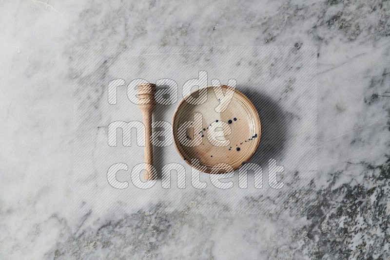 Multicolored Pottery Bowl with wooden honey handle on the side on grey marble flooring, Top view