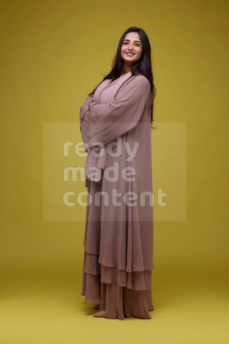 A woman Posing on a Yellow Background wearing Brown Abaya