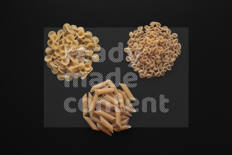 Different pasta types in bunches on black background