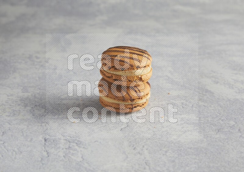 45º Shot of two light brown  Almond Cream macarons  on white  marble background