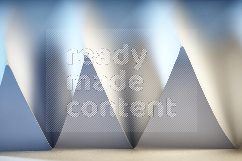 A close-up abstract image showing sharp geometric paper folds in white and blue gradients