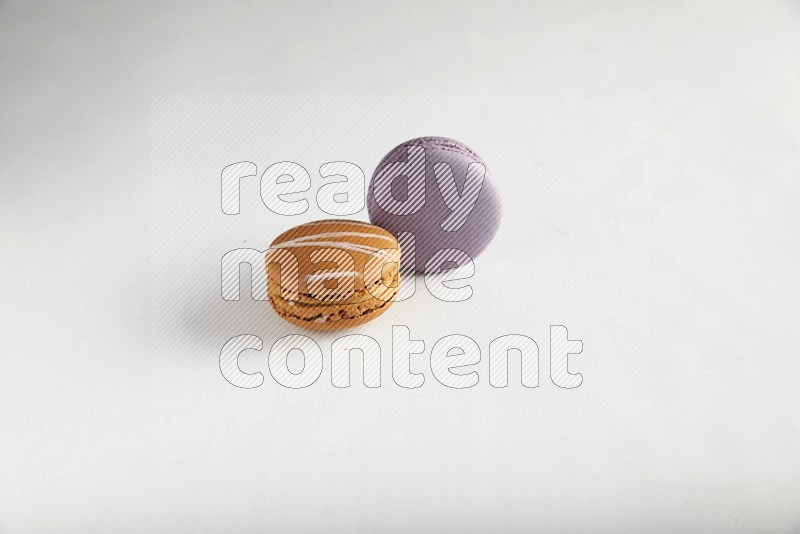 45º Shot of of two assorted Brown Irish Cream, and Purple Blueberry macarons on white background