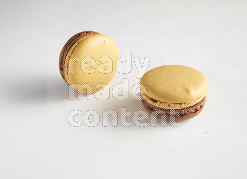 45º Shot of two Yellow and Brown Chai Latte macarons on white background