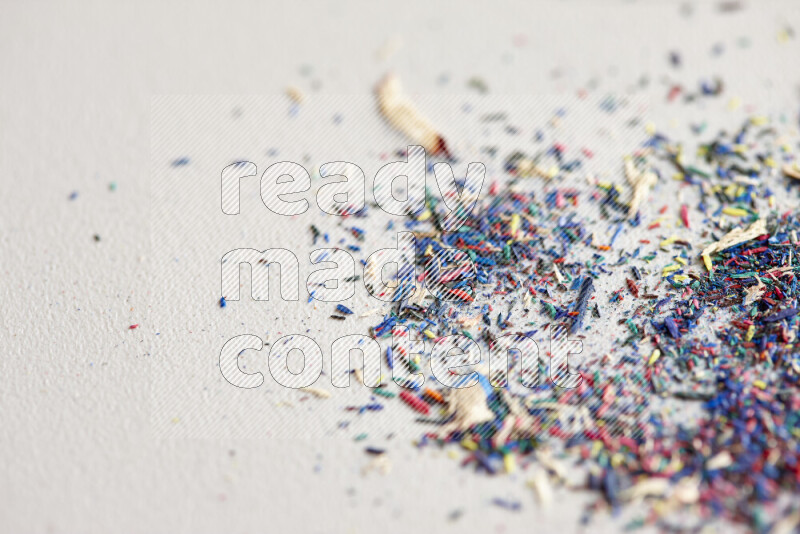 This image showcases a vibrant multicolored pencil shavings scattered on grey background