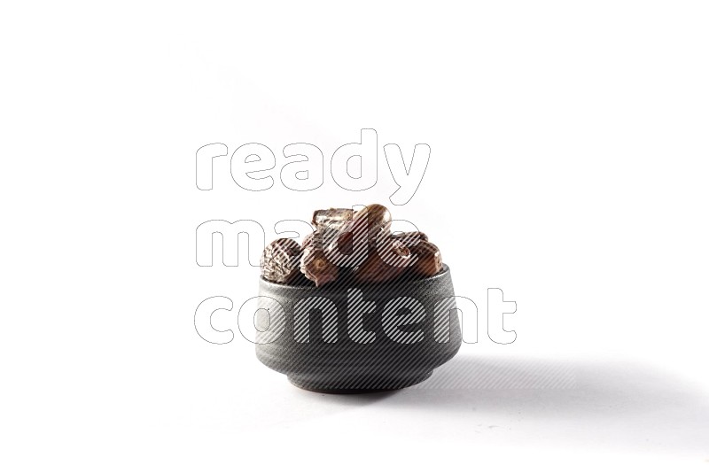 Dates in a black pottery bowl on white background