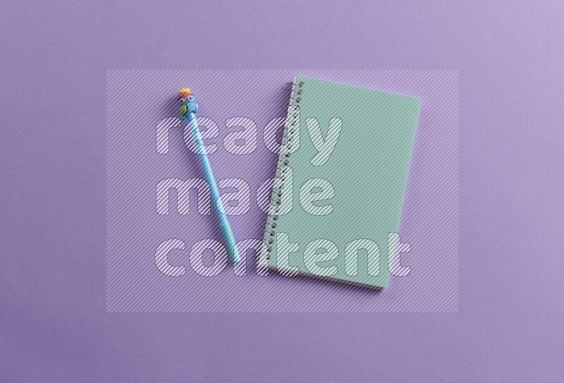 A blue notebook with school supplies on purple background