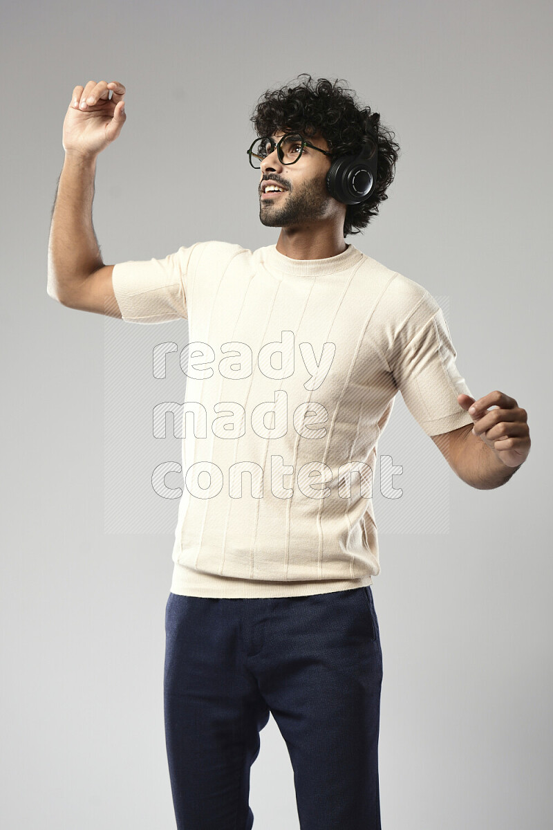 A man wearing casual standing and putting on headphones on white background