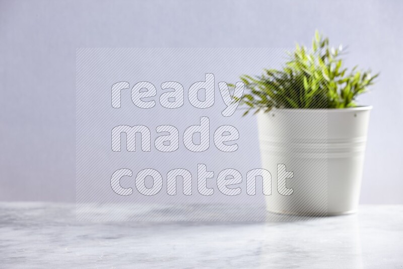 Artificial plant in white pot on grey marble background