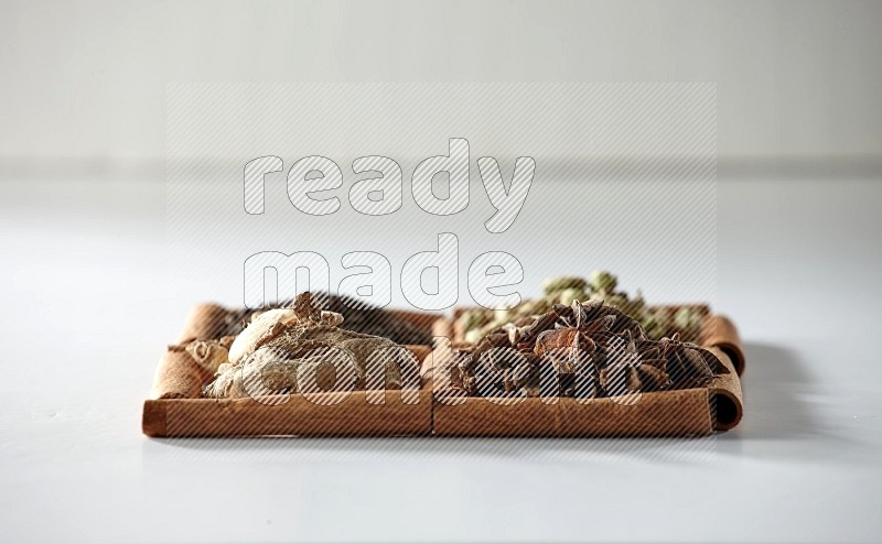 4 squares of cinnamon sticks full of tea, cardamom, star anise and ginger on white flooring