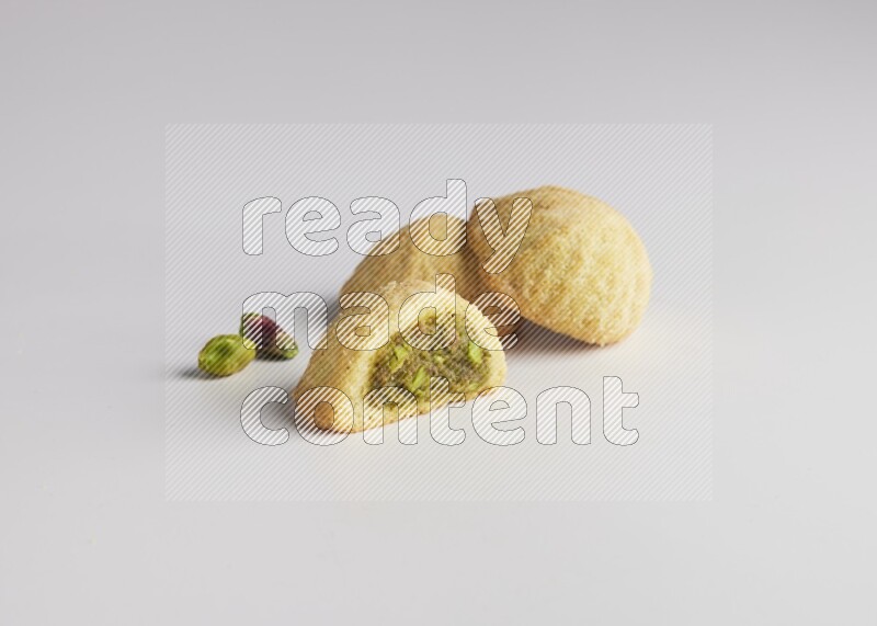 Three Pieces of Maamoul filled with pistachio paste  one of them is cut direct on white background