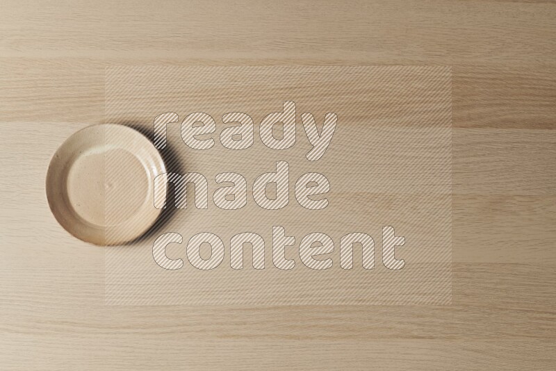 طبق من الفخار باللون البيج على خلفية خشبية فاتحة