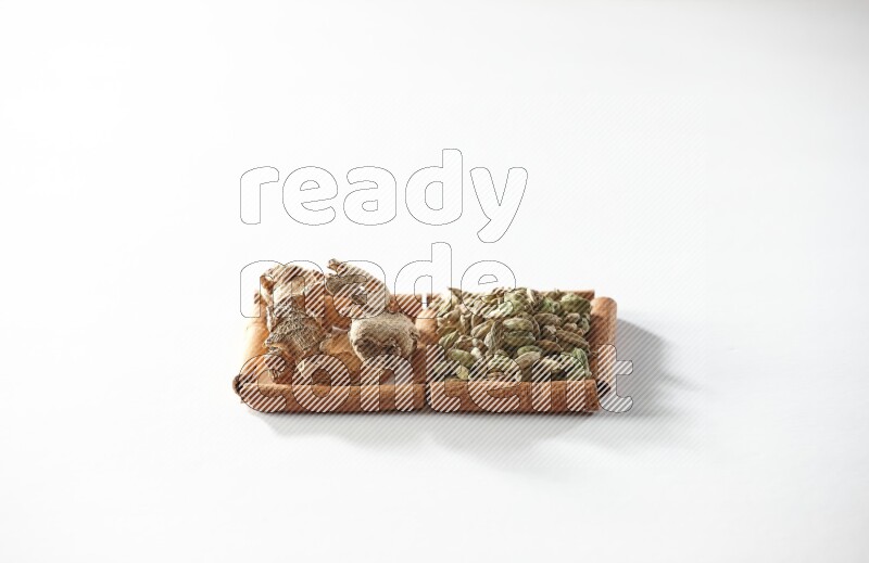 مربعان من أعواد القرفة ممتلئان بحبوب الهيل والزنجبيل المجفف علي خلفية بيضاء