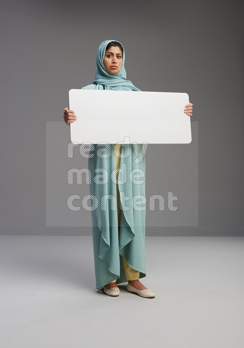 Saudi Woman wearing Abaya standing holding board on Gray background