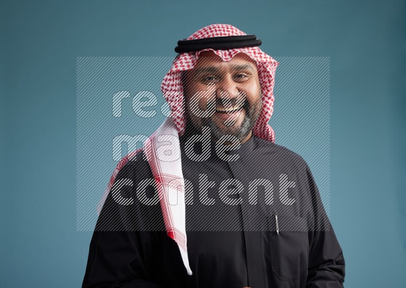 Saudi Man with shimag Standing Interacting with the camera on blue background