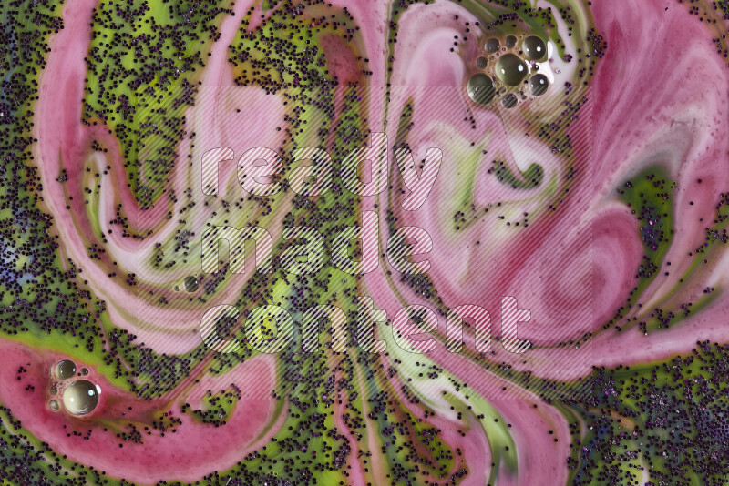 A close-up of sparkling purple glitter scattered on swirling green and red background