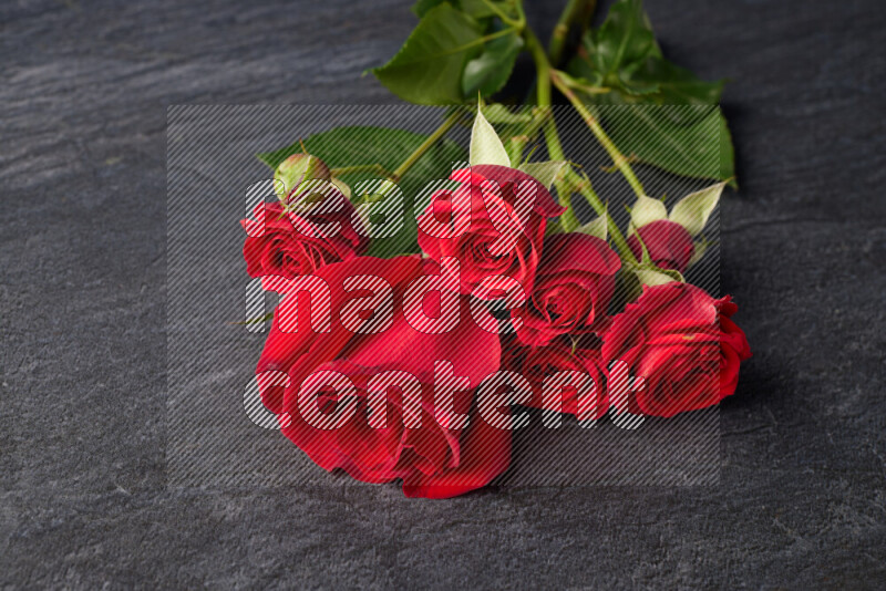 Red roses in different sizes on black marble background