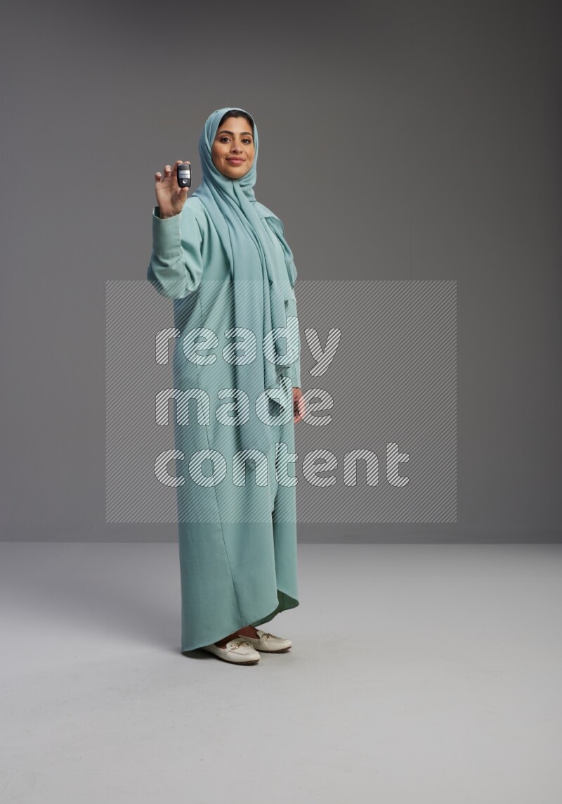 Saudi Woman wearing Abaya standing holding car key on Gray background
