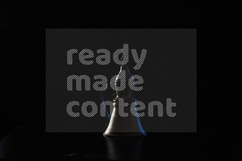 A turkish coffee pot with colored rim light against black background