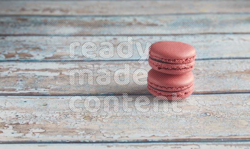 45º Shot of two Pink Raspberry macarons on light blue wooden background