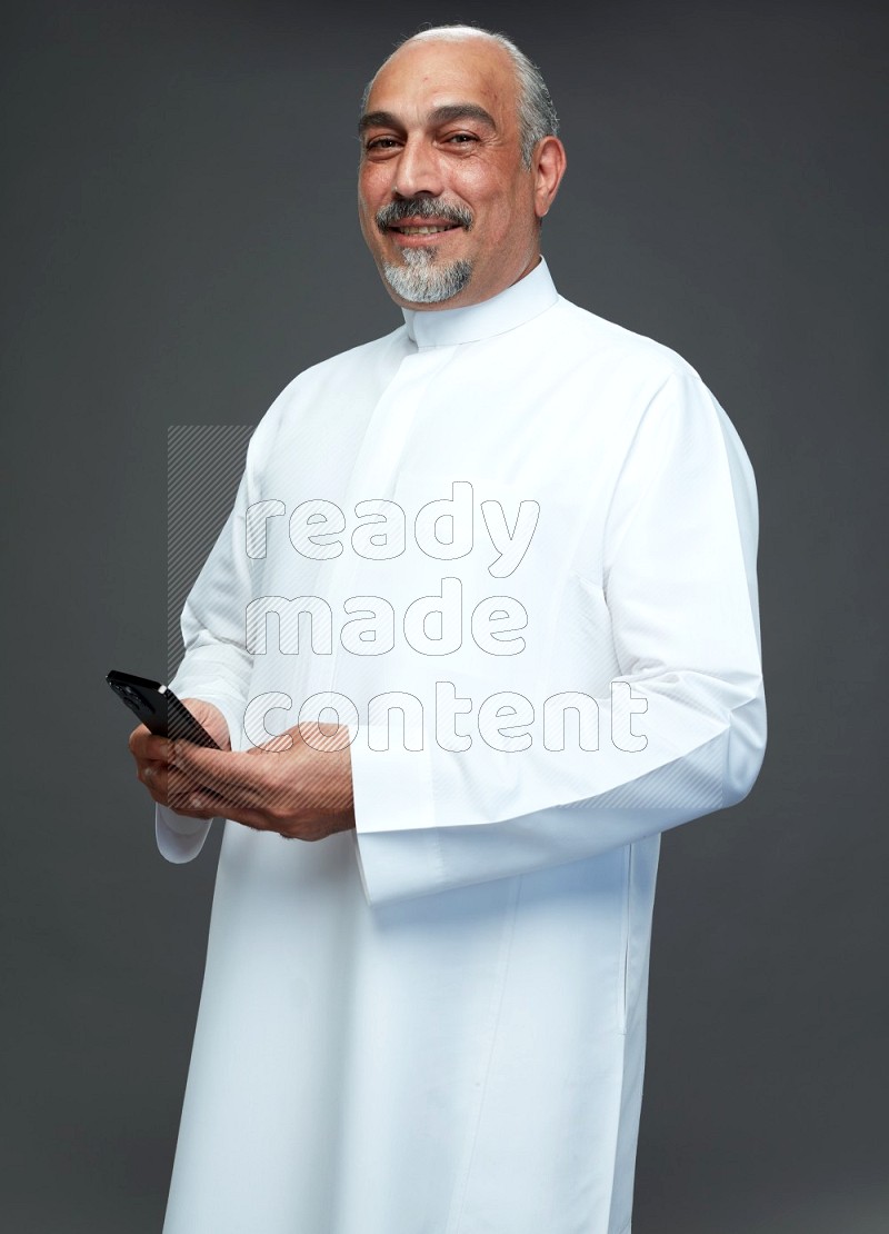 Saudi man without shomag Standing texting on phone on gray background