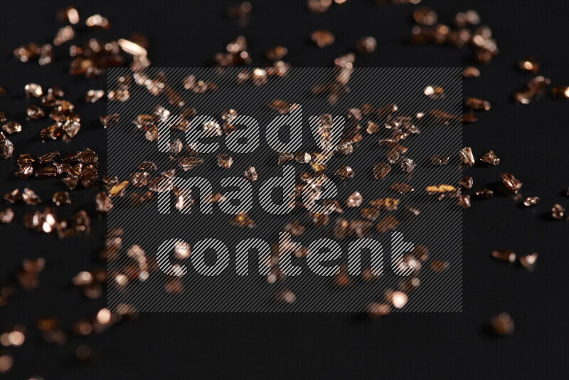 قطع زجاجية برونزية لامعة متناثرة على خلفية سوداء