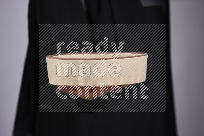 A woman in black abaya holding different pottery essentials in different positions
