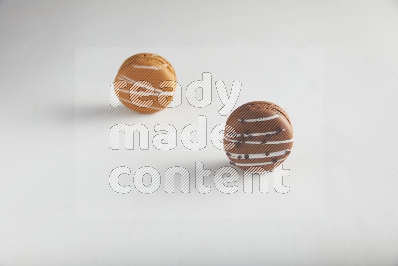 45º Shot of of two assorted Brown Irish Cream, and Brown white Chocolate Caramel macarons on white background