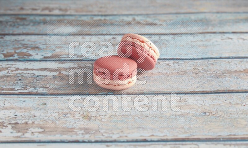 45º Shot of two Pink Litchi Raspberry macarons on light blue wooden background