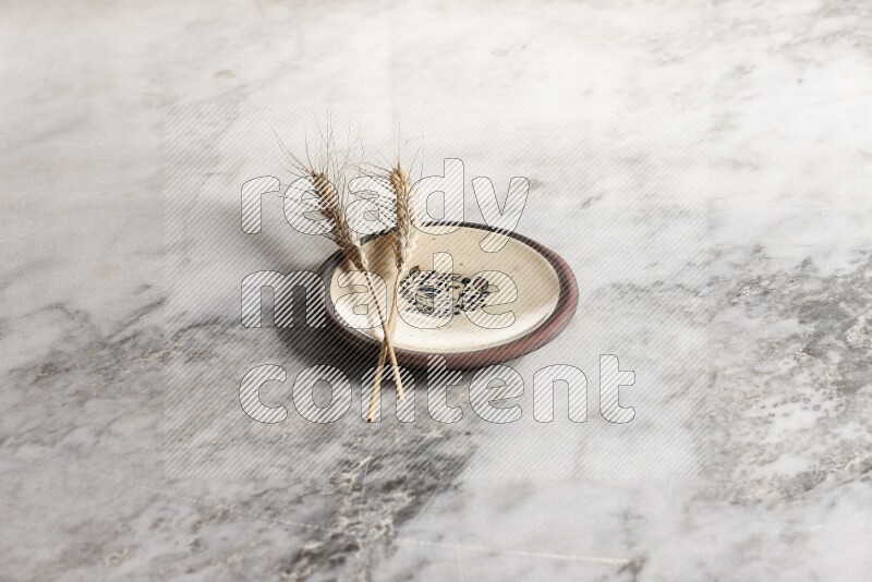 Wheat stalks on decorative pottery plate on grey marble background