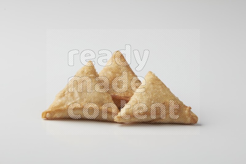 Three fried sambosas on a white background