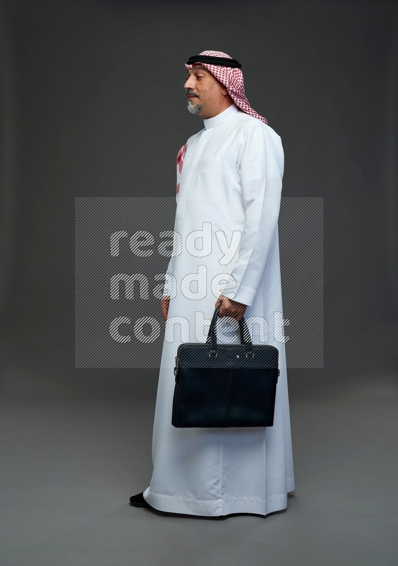 Saudi man with shomag Standing holding bag on gray background