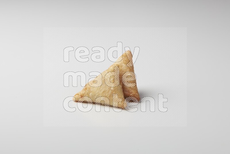 Two fried sambosas on a white background