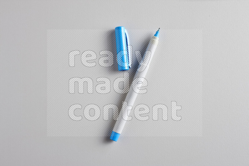 A close-up showing an open single coloring pen with a cap on grey background