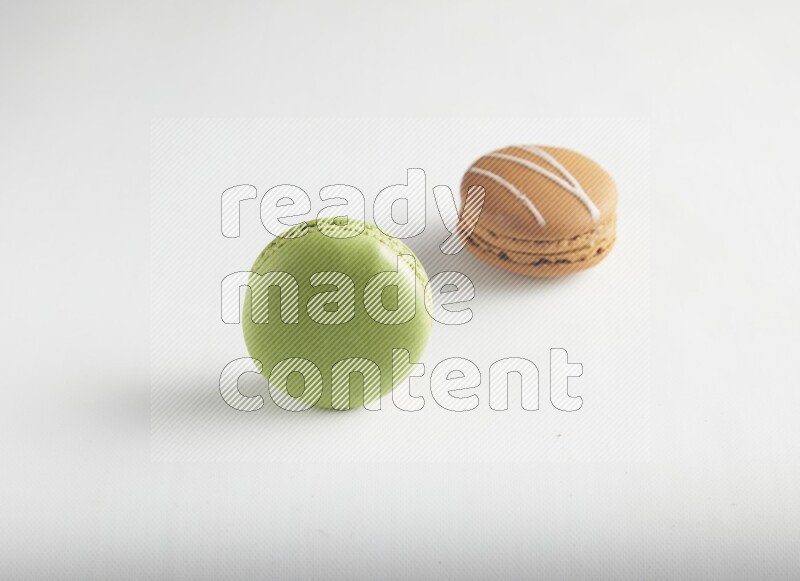 45º Shot of of two assorted Brown Irish Cream, and Green Pistachio macarons on white background