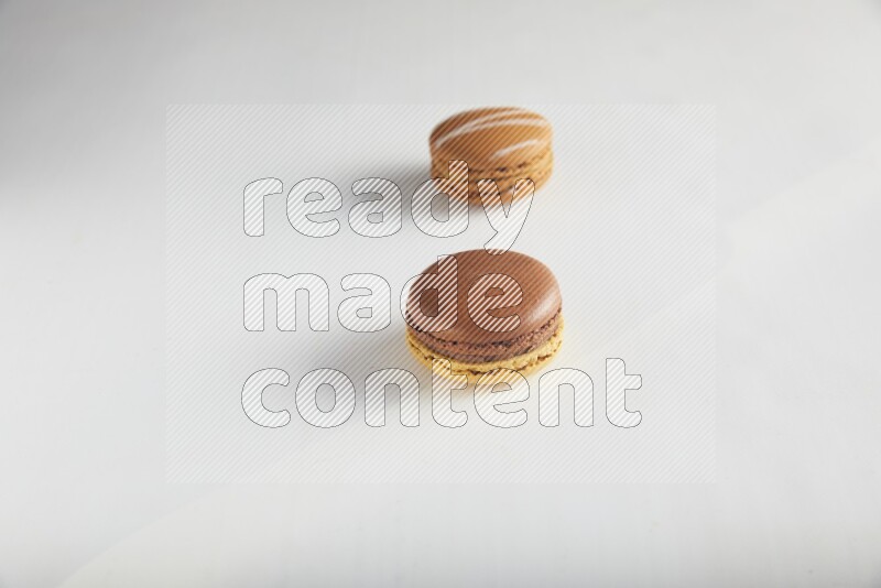 45º Shot of of two assorted Brown Irish Cream, and Yellow, and Brown Chai Latte macarons on white background