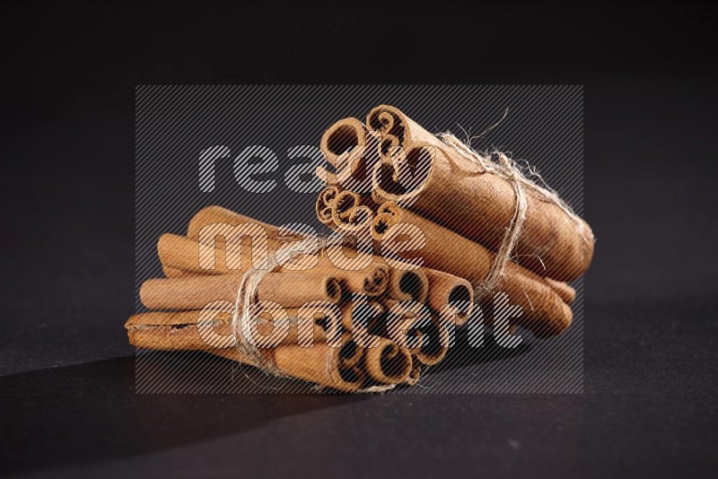 Two bounded stacks of cinnamon sticks on black background