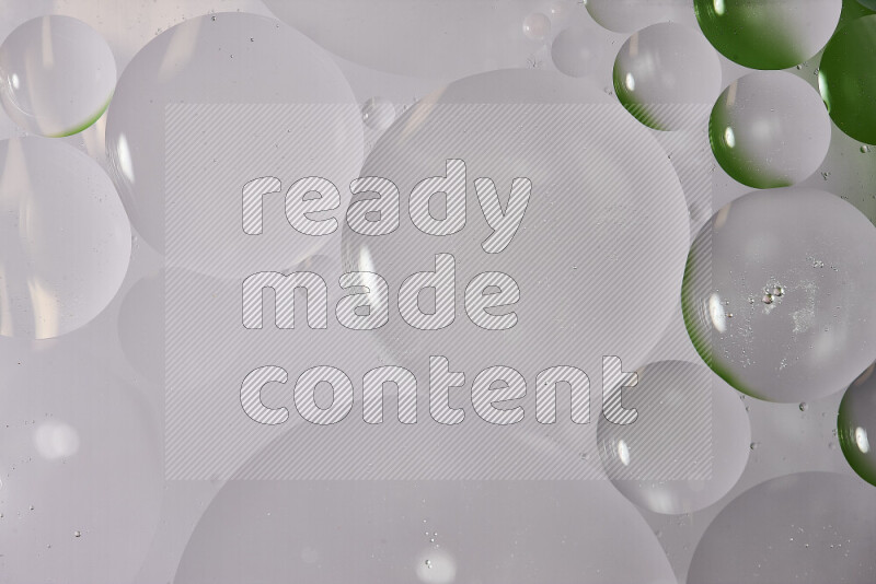 Close-ups of abstract oil bubbles on water surface in shades of white and green