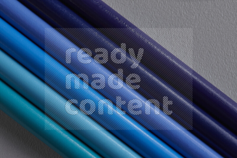 مجموعة من أقلام الرصاص الملونة مرتبة لتعرض تدرجا من الألوان الزرقاء علي خلفية رمادية