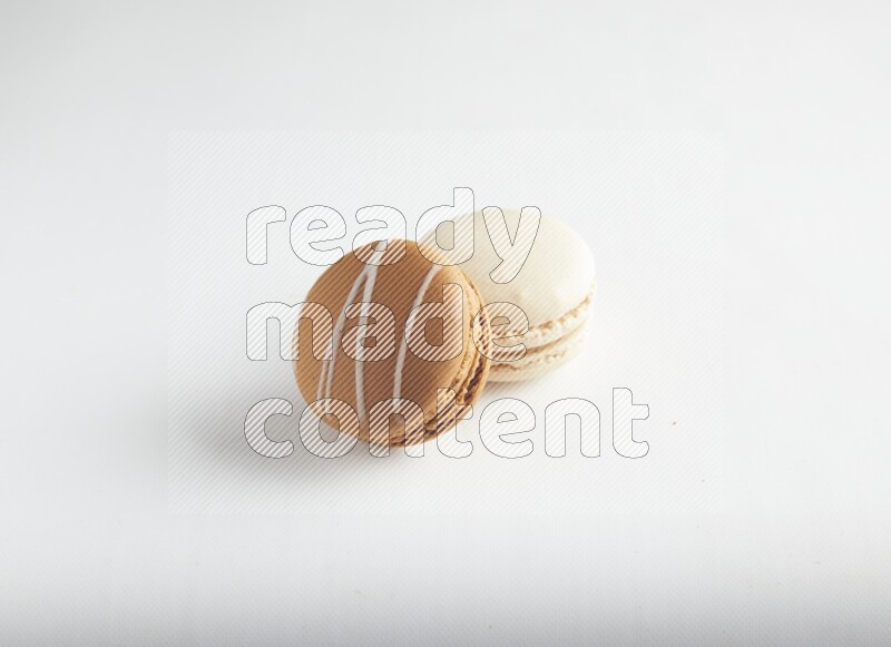 45º Shot of of two assorted Brown Irish Cream, and White Caramel fleur de sel macarons on white background